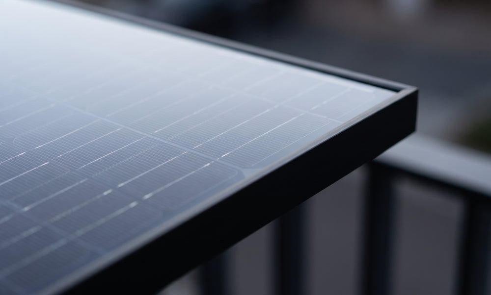 Nahaufnahme der Ecke eines Full-Black-Solarmoduls mit schwarzem Aluminiumrahmen am Balkongeländer